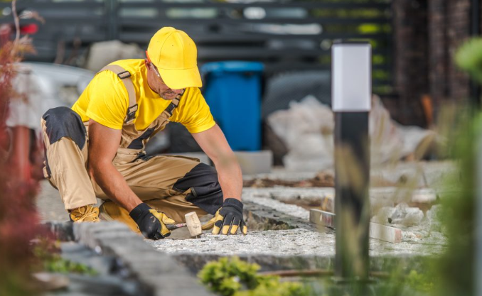 Landscaper laying patio with printed blueprints